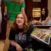 student discusses project, kneeling on ground in front of posters